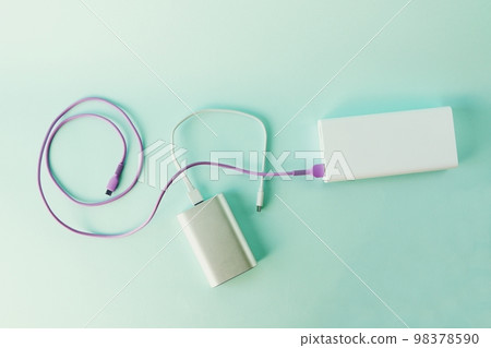 Power bank, external battery and usb wire on the table, universal mobile battery for charging gadgets, for recharging a smartphone Power bank, external battery and usb wire on the table, universal mobile battery for charging gadgets, for recharging a smartphone 98378590