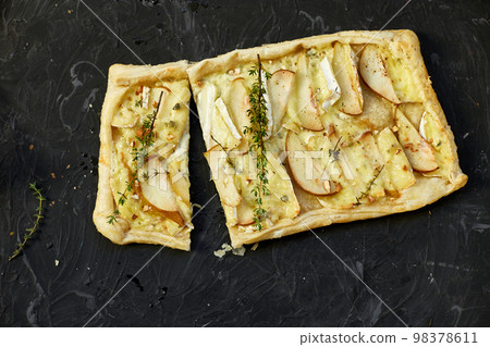 Pie baked in puff pastry with gorgonzola cheese and pears on black table 98378611