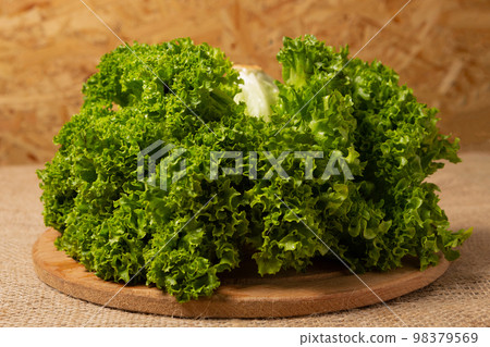 Heap of lettuce on a round wooden board, close-up 98379569