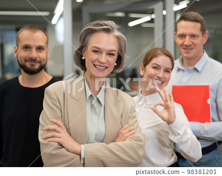 Portrait of four office workers. A gray-haired mature woman, a Caucasian man, a bearded man and a red-haired woman.  98381201