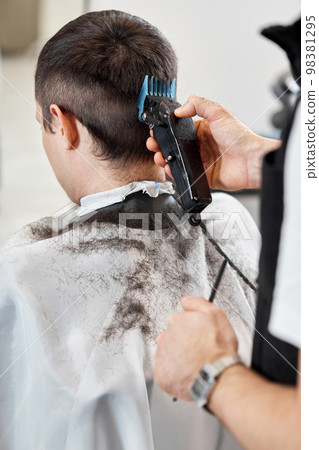 Barber shaving caucasian man in barber shop. 98381295