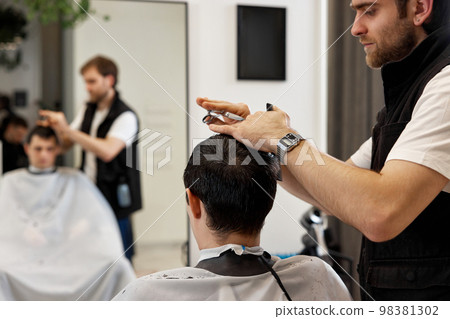 hairdresser does haircut for caucasian bearded man 98381302