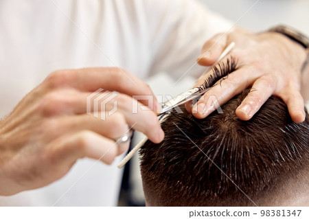 hairdresser does haircut for man using comb and grooming scissors 98381347