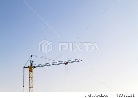 Yellow heavy duty industrial tower construction crane against blue sky with copy space Yellow heavy duty industrial tower construction crane against blue sky with copy space 98382131