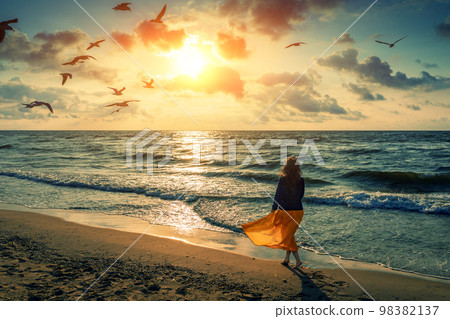 Seascape at sunrise with beautiful sky. Woman on the beach 98382137