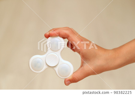 White fidget spinner toy in hand of a child White fidget spinner toy in hand of a child 98382225