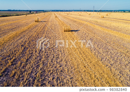 Aerial top view of the colorful geometric wheat fields with straw bales Aerial top view of the colorful geometric wheat fields with straw bales 98382840