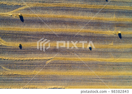 Aerial top view of the colorful geometric wheat fields with straw bales. Baling straw Aerial top view of the colorful geometric wheat fields with straw bales. Baling straw 98382843