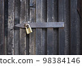 Padlock on a wooden wall. On wooden gates. 98384146