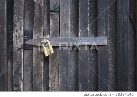 Padlock on a wooden wall. On wooden gates. 98384146