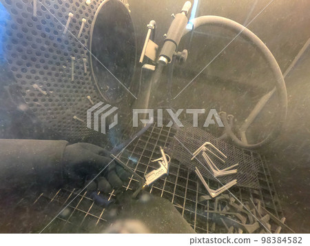 Shot blasting. Shot blasting of model printed on 3D printer from polyamide powder. A worker in sealed rubber gloves cleans the object by shot blasting in a shot blasting chamber. Industrial machine Shot blasting. Shot blasting of model printed on 3D printer from polyamide powder. A worker in sealed rubber gloves cleans the object by shot blasting in a shot blasting chamber. Industrial machine 98384582