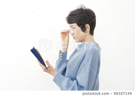 Middle-aged woman with presbyopia reading white background 98387149