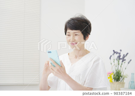 使用智能手機白色背景的中年婦女 98387184