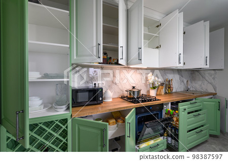 Doors open and drawers pulled out at new green and white kitchen furniture 98387597