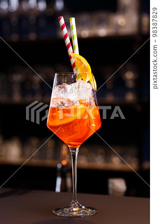 Orange cocktails with ice cubes and straws on the bar counter. Orange cocktails with ice cubes and straws on the bar counter. 98387829
