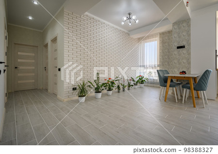 Trendy white studio apartment with a dining table and row of green plants Trendy white studio apartment with a dining table and row of green plants 98388327