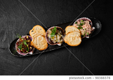 Set of raw fish snack in scallop shell on black background 98388378