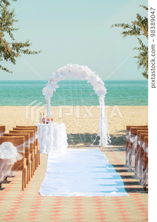 Wedding ceremony arch with white flowers on sea background Wedding ceremony arch with white flowers on sea background 98389047