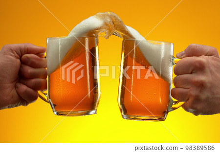 Two glasses of beer in cheers gesture, splashing. Two glasses of beer in cheers gesture, splashing. 98389586
