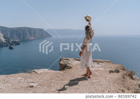 Side view portrait of a pensive young woman at sunset with a coastal city and mountains in the background. The concept of travel and peace Side view portrait of a pensive young woman at sunset with a coastal city and mountains in the background. The concept of travel and peace 98389742