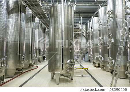 Large modern wine barrels at the winery, the concept of a large factory, production. Silver colored barrels, silver pipes on the ceiling. Large modern wine barrels at the winery, the concept of a large factory, production. Silver colored barrels, silver pipes on the ceiling. 98390496