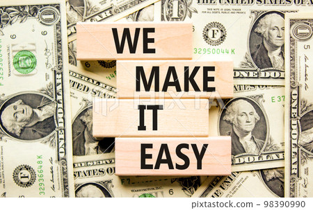 We make it easy symbol. Concept words We make it easy on wooden cubes. Beautiful background from dollar bills. Business motivational we make it easy concept. Copy space. 98390990