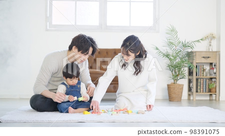 Family of three playing in the living room Family of three playing in the living room 98391075