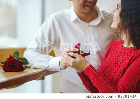 Handsome man proposing a beautiful woman to marry him in restaurant. Valentines day concept. Handsome man proposing a beautiful woman to marry him in restaurant. Valentines day concept. 98391434