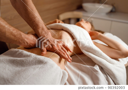 Masseur's hands massaging the patient's abdomen. Man makes an anti-cellulite belly massage to a woman Masseur's hands massaging the patient's abdomen. Man makes an anti-cellulite belly massage to a woman 98392003