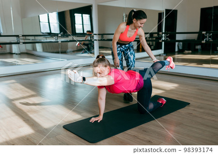 Fitness trainer and mentee over gym room background. Sport and healthy active lifestyle concept. Indoor workout 98393174