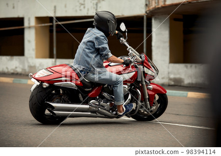 Handsome bearded biker with classic style black motorcycle. Cafe racer in garage. Handsome bearded biker with classic style black motorcycle. Cafe racer in garage. 98394114