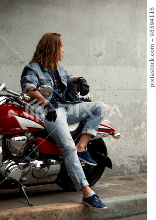 Handsome bearded biker with red motorcycle in classic style. Cafe racer in the garage. Handsome bearded biker with red motorcycle in classic style. Cafe racer in the garage. 98394116