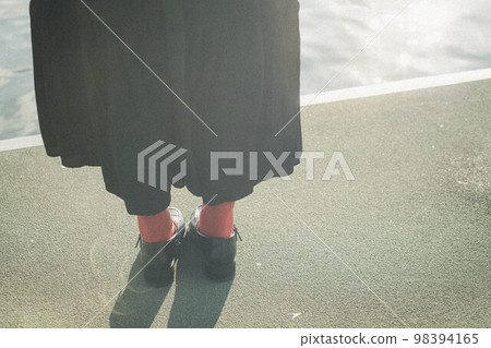 Feet of a woman standing in a seaside harbor 98394165