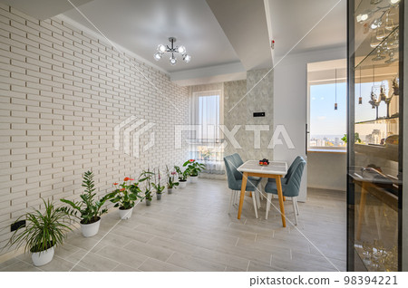 A minimalist white studio with a kitchen and dining table 98394221
