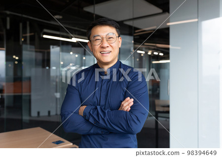 Portrait of successful asian boss inside office, businessman with crossed arms smiling and looking at camera, man in shirt and glasses happy with result of achievement at work. Portrait of successful asian boss inside office, businessman with crossed arms smiling and looking at camera, man in shirt and glasses happy with result of achievement at work. 98394649