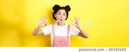 Excited beauty girl with bright makeup and summer clothes, showing okay signs and say wow, praise good promo deal, approve advertisement, yellow background Excited beauty girl with bright makeup and summer clothes, showing okay signs and say wow, praise good promo deal, approve advertisement, yellow background 98395688