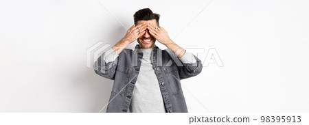 Happy smiling guy waiting with closed eyes for surprise, standing excited on white background 98395913