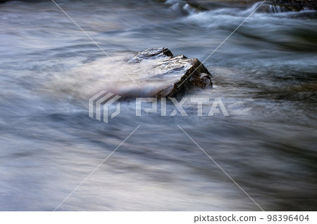 Stone in a river with fast moving water around 98396404