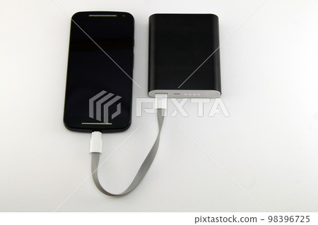Smartphone charging from black power bank isolated on white background. Smartphone and power bank concept. Smartphone charging from black power bank isolated on white background. Smartphone and power bank concept. 98396725
