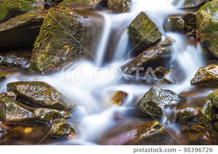 Small waterfall with foamy water and wet stones Small waterfall with foamy water and wet stones 98396726