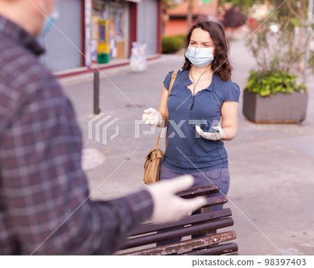 Couple in protective medical masks against coronavirus communicate on street 98397403