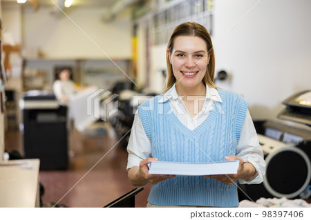 Cheerful woman printing shop manager holding ream of paper 98397406