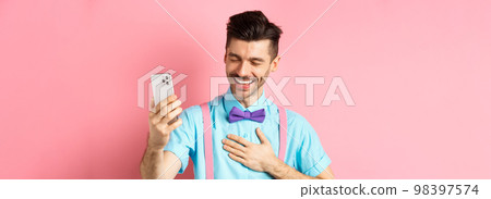 Image of handsome guy laughing during video chat, having mobile conversation and chuckle from something funny, standing on pink background 98397574
