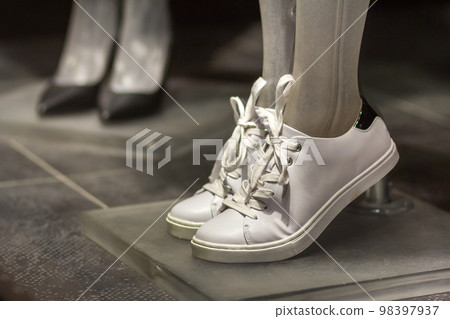 Pair of fashionable new comfortable leather light white sport running female shoes sneakers isolated on shop shelf background. Style, design and fashion, modern footwear for gym and summer training. Pair of fashionable new comfortable leather light white sport running female shoes sneakers isolated on shop shelf background. Style, design and fashion, modern footwear for gym and summer training. 98397937