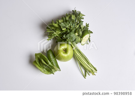 some green vegetables on a white surface with an apple and celery in the middle, next to it some green vegetables on a white surface with an apple and celery in the middle, next to it 98398958