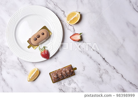 some desserts on a white plate with lemon slices and strawberries in the photo is taken from above it 98398999
