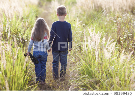 Little boy and little girl standing holding hands looking on horizont. Rear view. Little boy and little girl standing holding hands looking on horizont. Rear view. 98399480