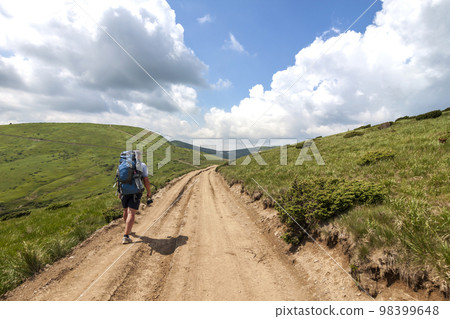 Hiker climbing up mountain in summer sunny day 98399648