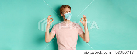 Covid-19, pandemic and lifestyle concept. Cheerful redhead man in medical mask showing okay signs in approval, like and praise product, looking left at copy space Covid-19, pandemic and lifestyle concept. Cheerful redhead man in medical mask showing okay signs in approval, like and praise product, looking left at copy space 98399718