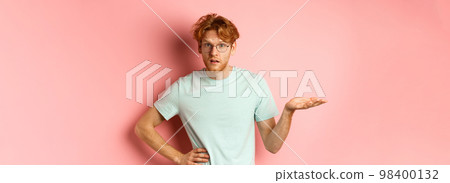 So what. Confused redhead man raising hand and shrugging, looking puzzled, dont understand something, standing over pink background 98400132